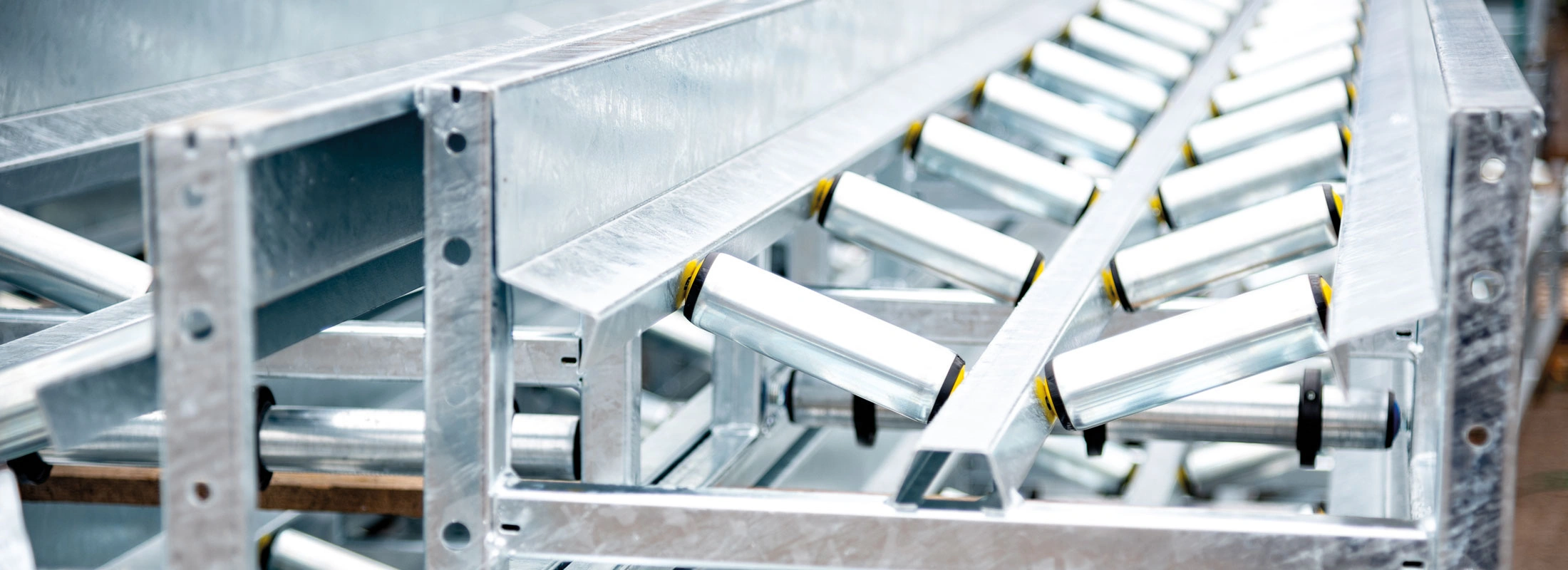 Detailansicht eines robusten, verzinkten Fördertechniksystems mit schräg angeordneten Rollen zur effizienten Materialbewegung in der Industrie.